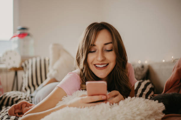 Millennial girl using her phone on the bed stock photo