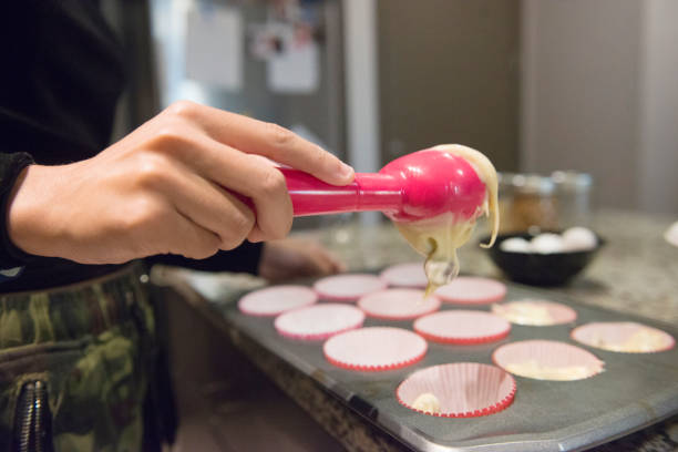 Millennial Hispanic Woman Scooping Cupcake Batter into Baking Pan This is a color, royalty free photograph of a young 20 year old Millennial woman baking cupcakes from scratch at home in the kitchen in Orlando, Florida, USA. This is a close up of her hand as she scoops the freshly made dessert batter into a cupcake baking pan. hot puerto rican woman stock pictures, royalty-free photos & images