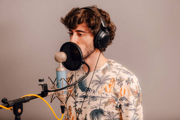 Millennial male singer on headphones singing at recording home studio stock photo