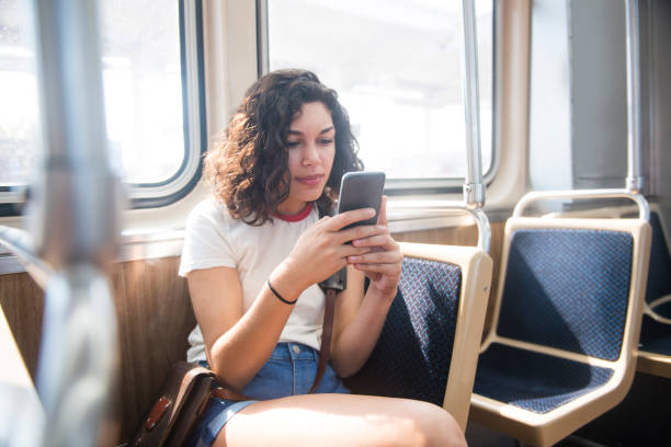 Millennial Puerto Rican Woman On Social Media and Train Chicago A beautiful, millennial Puerto Rican woman in her 20's travels locally in Chicago, Illinois, a major USA city on public transportation. She looks at her phone spending time on social media as she rides the elevated train. puerto rican women stock pictures, royalty-free photos & images