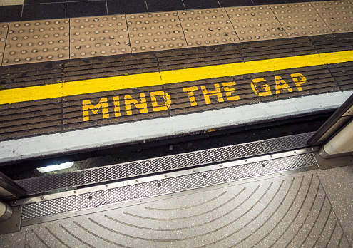 London, UK - A 'Mind The Gap' warning, painted on the platform of a London Underground station, as seen from the point of view of a passenger about to get off the train.