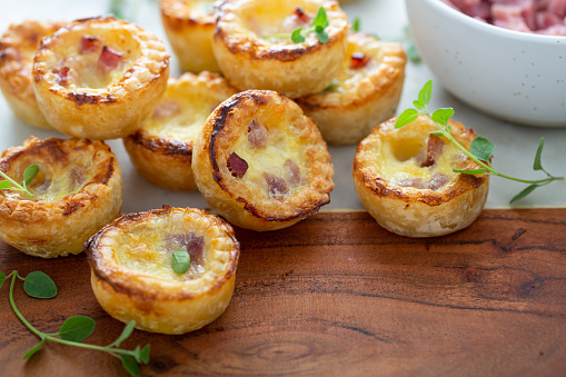Mini ham and cheese quiches freshly baked on a marble board ready to eat