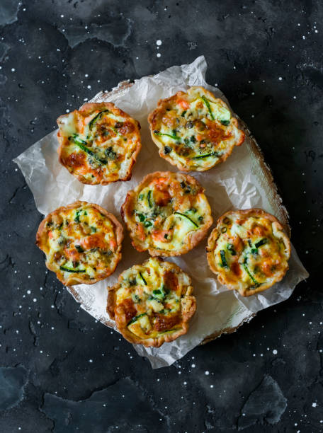 Mini quiche with salmon and zucchini on a dark background, top view. Delicious snacks, tapas, appetizers stock photo