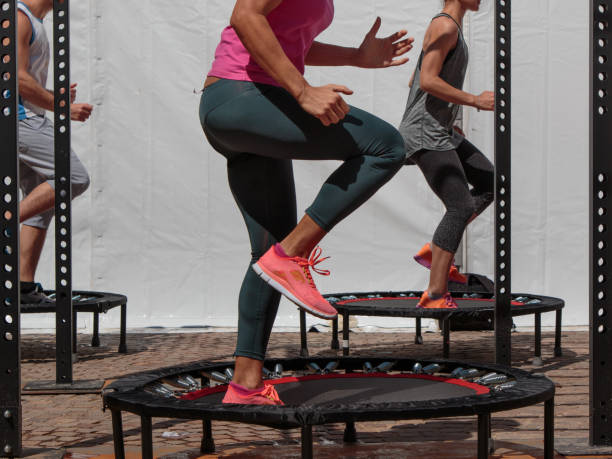 mini allenamento trampolino: ragazza che fa esercizio di fitness in classe in palestra - tappeto elastico foto e immagini stock