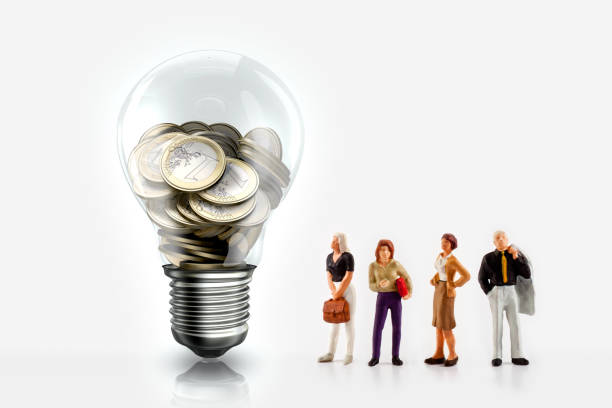 Miniature people in front a light bulb with Euro coins inside stock photo
