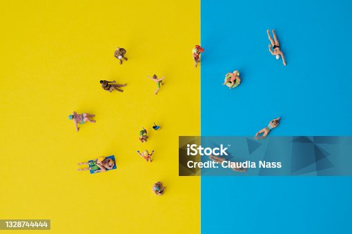 istock miniature people on yellow and blue paper, holiday situation with swimming or sunbathing people 1328744444