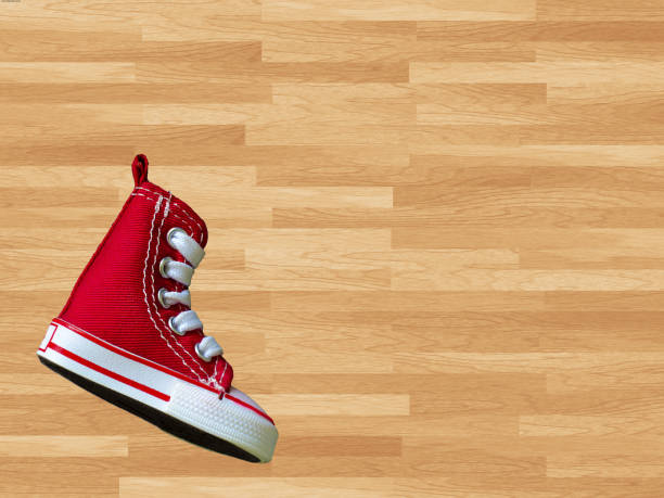 Miniature red baskeball shoe on wooden floor as background stock photo