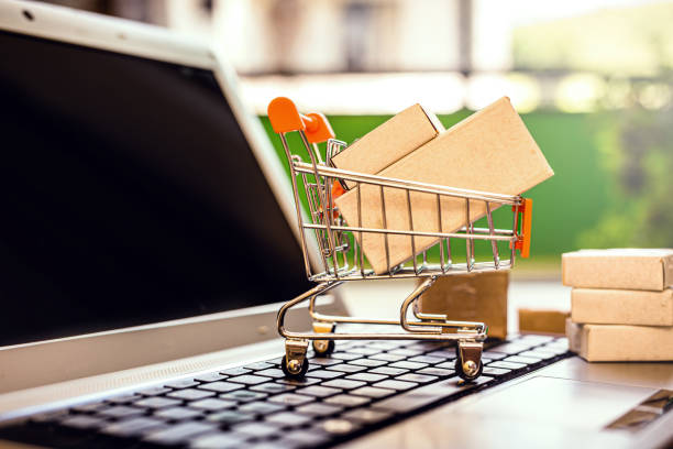 miniature supermarket shopping cart over personal computer, online shopping concept, buy from home stock photo