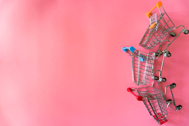 Minimal shopping online concept, Colorful paper shopping bag and trolley go down from floating pink background for copy space. Customer can buy everthing form home and the messenger will deliver. stock photo