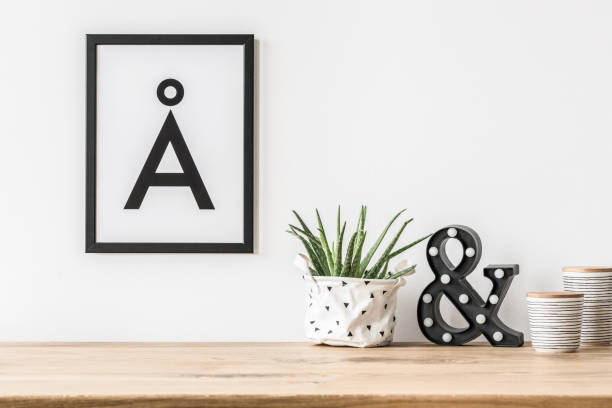 Minimalist poster and led light A minimalist aesthetic letter poster in a frame on a white wall above a led letter light and a succulent in fabric planter scandinavian culture photos stock pictures, royalty-free photos & images