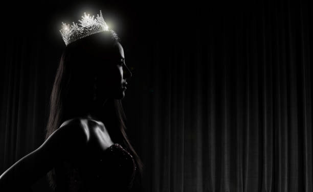 Miss Pageant Contest silhouette with Diamond Crown Portrait of Miss Pageant Beauty Contest in sequin Evening Ball Gown long dress with sparkle light Diamond Crown, silhouette low key exposure with curtain, studio lighting dark background dramatic beauty pageant stock pictures, royalty-free photos & images