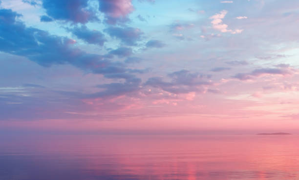 Misty Lilac Seascape With Pink Clouds Misty lilac seascape - pink and blue clouds over the water of calm Lake Onega and the small island in the White Nights season - Russia, Republic of Karelia. Soft focus. morning stock pictures, royalty-free photos & images