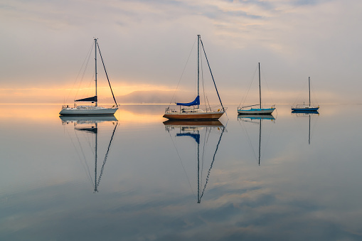 Boats and reflections with mist over the bay. Koolewong on the Central Coast, NSW, Australia.