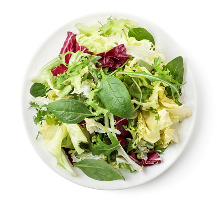 Mix salad in a plate close-up on a white background. Top view.