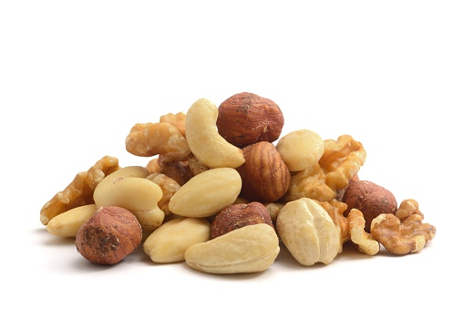 A pile of shelled hazelnuts, walnuts,cashew nuts and almonds, isolated on a white background.