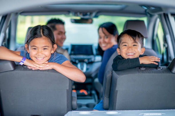Mixed Race Family of Four Road Trip stock photo A mixed race family of four, consisting of a Mother, Father, son and daughter look out the back end of the vehicle.  They are smiling and ready to start their road trip adventure. philippine girl stock pictures, royalty-free photos & images