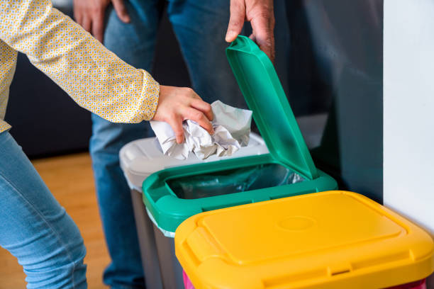 Mixed Race Father and Daughter Recycling Paper and Throwing it into a Garbage Bin stock photo