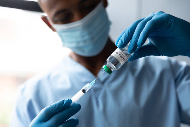 混合種族男醫生拿著科維德 - 19 疫苗接種戴著面罩 - south africa covid 個照片及圖片檔