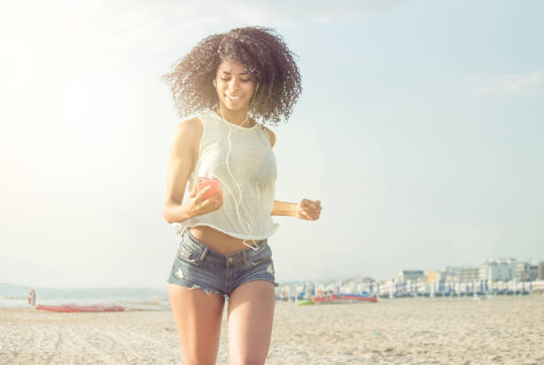 mixed race modern woman enjoy jogging on beach stock photo