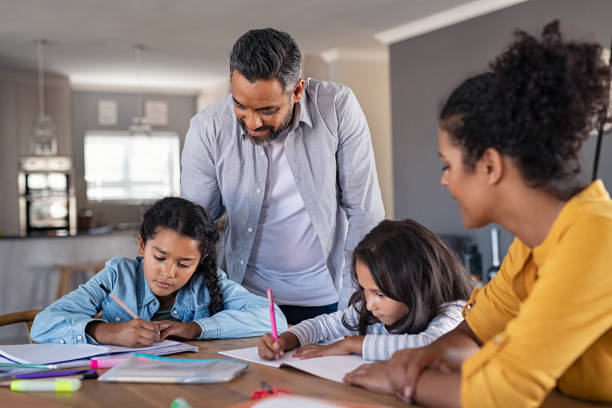 Mixed race parents helping children in homework at home Indian parents helping children with their homework at home. Middle eastern father and african mother helping daughters studying at home. Little girls completing their exercises with the help of dad and mom, homeschooling concept. homework stock pictures, royalty-free photos & images