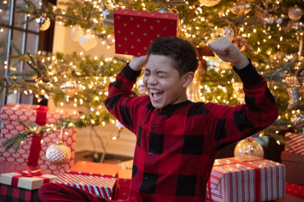 Mixed race teenager boy opening Christmas presents stock photo