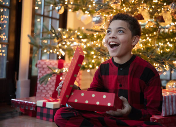 Mixed race teenager boy opening Christmas presents stock photo