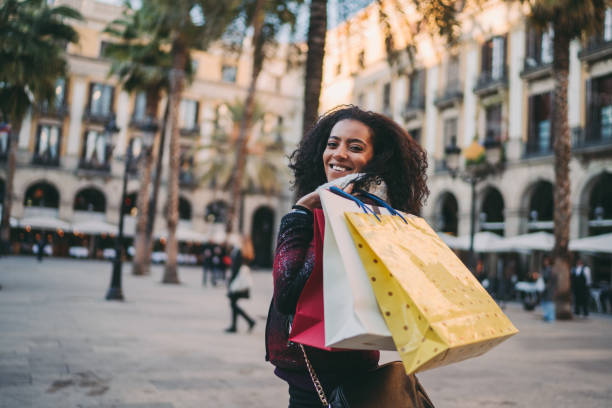 Mixed race woman in Europe enjoying a shopping Smiling woman with shopping bags walking outside and looking at camera madridshop stock pictures, royalty-free photos & images
