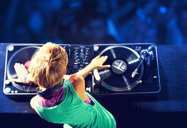 Mixing it up for the crowd Rear-view shot of a trendy young DJ mixing up some music with a crowd in the background dance music stock pictures, royalty-free photos & images