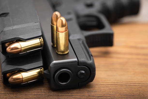 9 mm. ammunition magazines and automatic hand gun on wooden background - gun violence 個照片及圖片檔