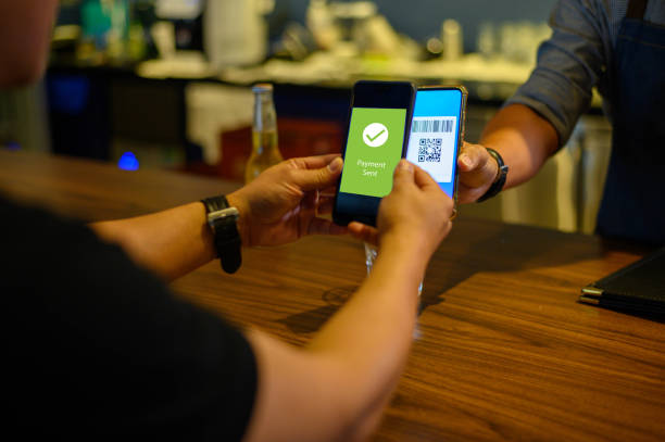 Mobile payment in cafe Image of Asian man scanning QR code from cashier smartphone to accepting mobile payment. contactless payment stock pictures, royalty-free photos & images