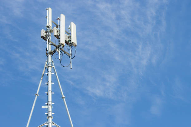 mobile phone communication repeater antenna against a blue sky background stock photo