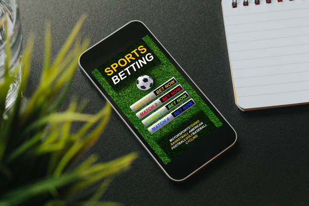 Mobile phone with sports betting website app in the screen. Sports betting website in a mobile phone screen placed over a black desk. sport betting stock pictures, royalty-free photos & images