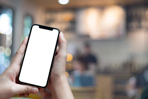 Mockup image of hand holding mobile phone with blank white Full screen in cafe For Graphic display montage. stock photo