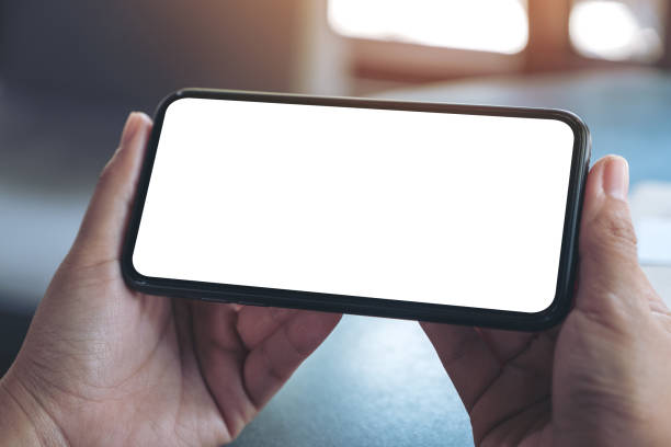 imagem de maquete de mãos segurando um celular preto com tela em branco do desktop horizontalmente - horizontal - fotografias e filmes do acervo