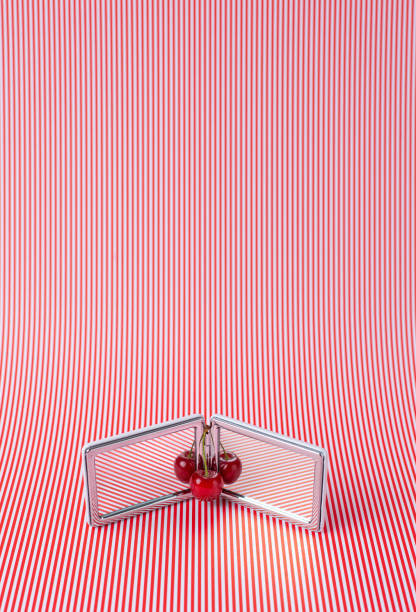 Modern abstract summer background with red thin stripes and cherry fruit reflecting in small mirror. stock photo