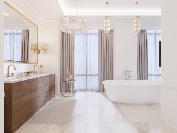 Modern bathroom with vanity and a mirror in a gold frame with sconces on the wall, a low table with decor, shower and a fashionable bath. stock photo