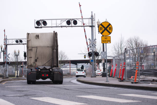 Modern Big Rig Semi-truck tractor moving by open railroad crossing stock photo