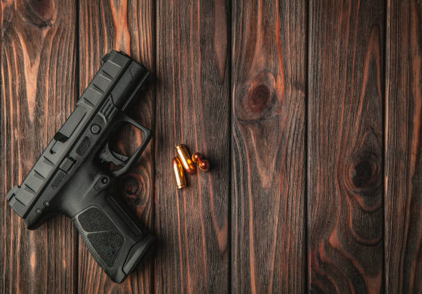 Modern black gun and ammunition  on a wooden background. Pistol. Weapons for sport and self-defense lie on the table. Modern black gun and ammunition  on a wooden background. Pistol. Weapons for sport and self-defense lie on the table. pistol stock pictures, royalty-free photos & images