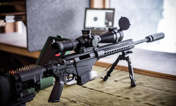 Modern bolt action rifle with scope and suppressor Modern bolt action rifle with scope and suppressor on the shooting range with a box of ammunition and a monitor in the background that displays target hits of the shooter nra stock pictures, royalty-free photos & images