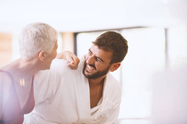 Modern couple Side view of a mature woman and younger man laughing together. They are enjoying vacation at the spa. cougar woman stock pictures, royalty-free photos & images