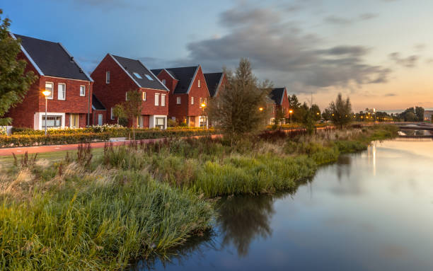Modern Eco friendly suburban street Long exposure night shot of Street with modern ecological middle class family houses with eco friendly river bank in Veenendaal city, Netherlands. riverbank stock pictures, royalty-free photos & images