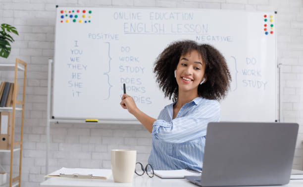 Modern education remotely. Cheerful african american woman points to blackboard and explains rules of english Modern education remotely. Cheerful young african american woman points to blackboard and explains rules of english online showing stock pictures, royalty-free photos & images