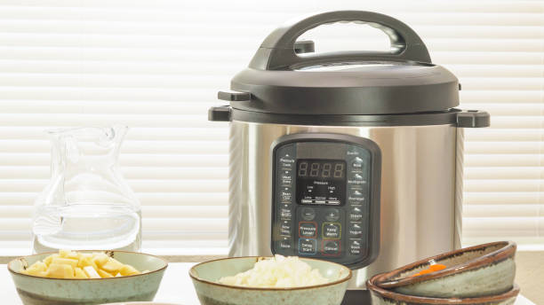 Modern electric multi cooker or Pressure cooker with some ingredients for cooking needs close up on kitchen table stock photo