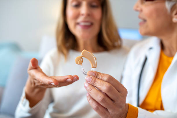Modern hearing aids Modern hearing aids.The choice of hearing aid in the doctor's office. Doctor showing hearing aid. Otolaryngologist giving hearing aid to patient. The hearing aid for a senior woman hearing aid stock pictures, royalty-free photos & images