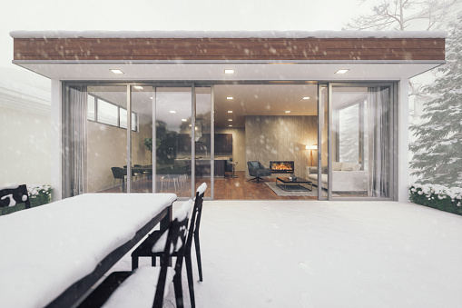 Exterior of a modern open plan luxury house with fireplace in snowy weather.
