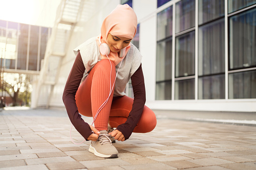 Modern Muslim sportswoman, tying her sports shoe