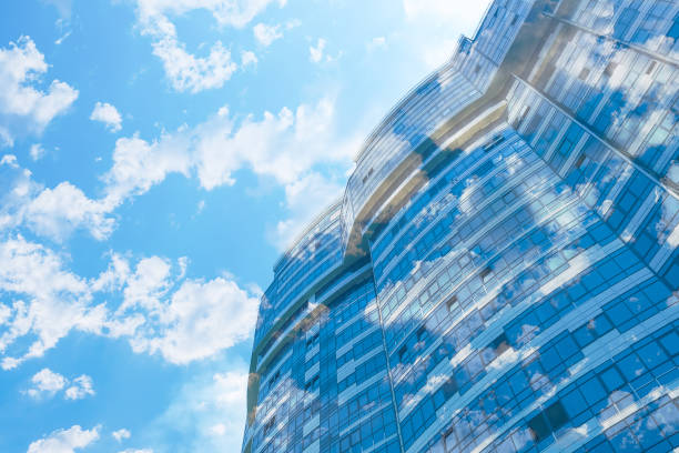 Modern office building with stained glass windows against the blue sky with clouds, multi exposure stock photo