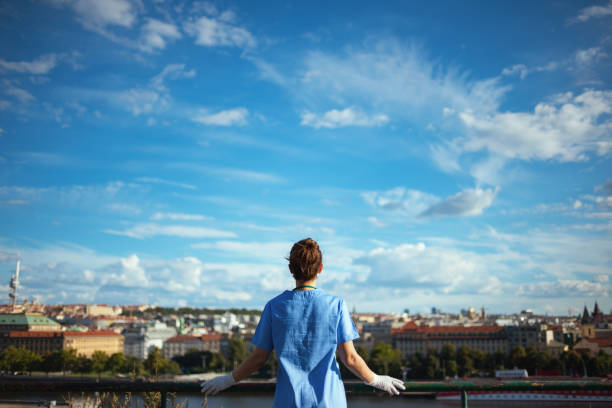 modern physician woman in scrubs outdoors in city against sky stock photo