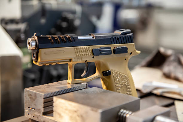 A modern pistol with a beige grip on a work table in a workshop. Service maintenance of weapons. Pistol repair. stock photo