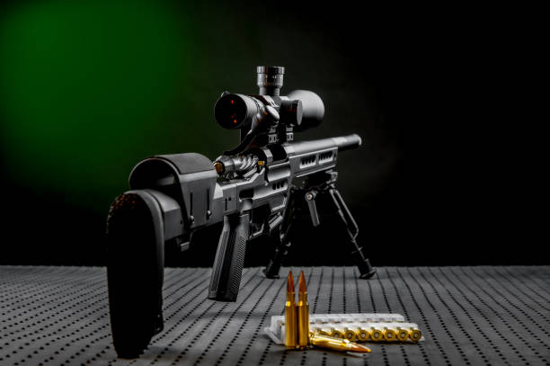 Modern powerful sniper rifle with a telescopic sight mounted on a bipod. Ammo and an additional magazine next to the rifle. stock photo